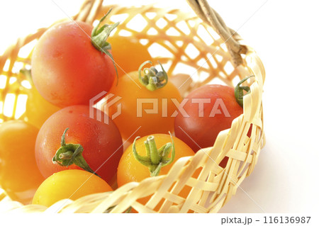 竹かごに沢山入っている黄色と赤色のミニトマトを白背景で撮影 116136987