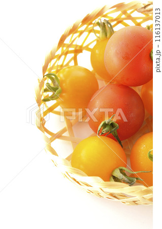 竹かごに沢山入っている黄色と赤色のミニトマトを白背景で撮影 116137013