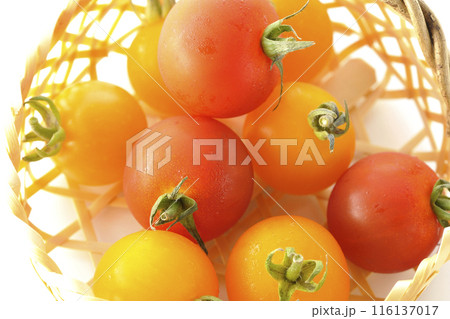 竹かごに沢山入っている黄色と赤色のミニトマトを白背景で撮影 116137017