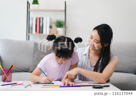 A woman is helping a little girl with her drawing A woman is helping a little girl with her drawing 116137044