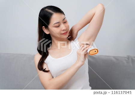 A beautiful woman is epilating her armpits using an IPL laser hair removal 116137045