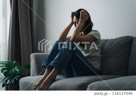 Unhappy lonely depressed woman is sitting on the couch. She looks sad and tired. Unhappy lonely depressed woman is sitting on the couch. She looks sad and tired. 116137046