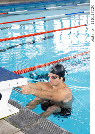 Caucasian boy with dark hair in goggles prepares for an indoor swim, copy space 116137220
