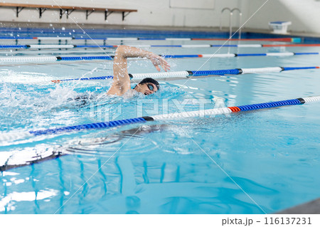 Caucasian young male swimmer wearing goggles, training indoors in swimming pool, copy space 116137231