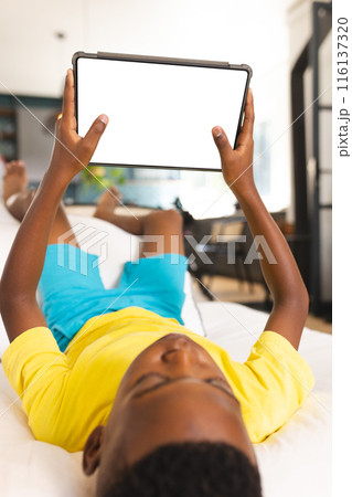 An African American boy holding tablet at home, wearing a yellow shirt, copy space An African American boy holding tablet at home, wearing a yellow shirt, copy space 116137320