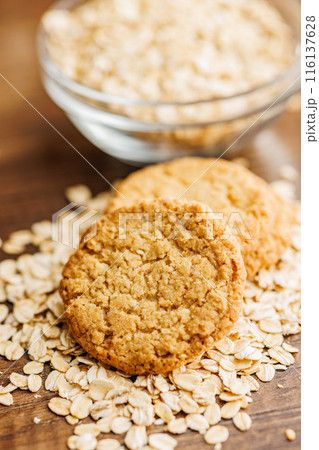 Tasty oatmeal cookies and rolled oat on wooden table. 116137628
