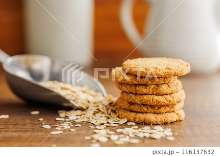 Tasty oatmeal cookies and rolled oat on wooden table. 116137632