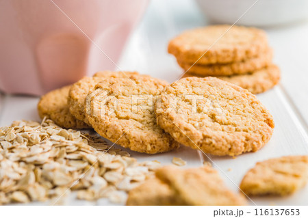 Tasty oatmeal cookies and rolled oat on white table. 116137653