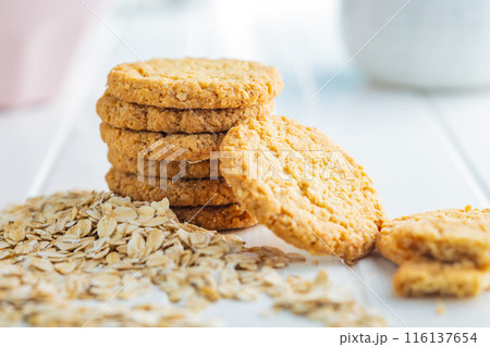 Tasty oatmeal cookies and rolled oat on white table. 116137654