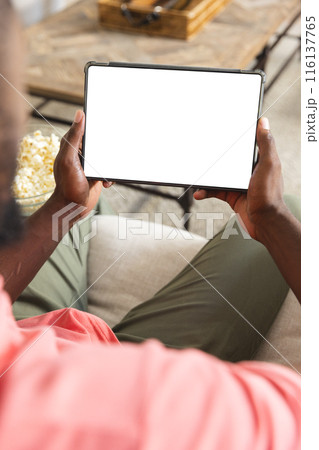 African American man relaxing at home, holding blank tablet screen with copy space 116137765