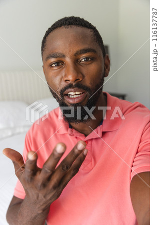 At home, African American man wearing pink shirt, talking on a video call At home, African American man wearing pink shirt, talking on a video call 116137787