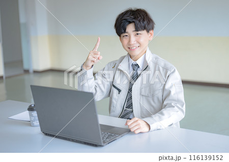 PCと指し示す若い作業服男性 116139152