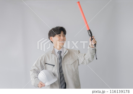 誘導とヘルメットを持つ若い作業服男性 誘導とヘルメットを持つ若い作業服男性 116139178