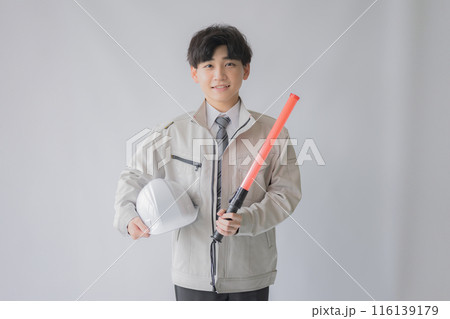 誘導とヘルメットを持つ若い作業服男性 誘導とヘルメットを持つ若い作業服男性 116139179