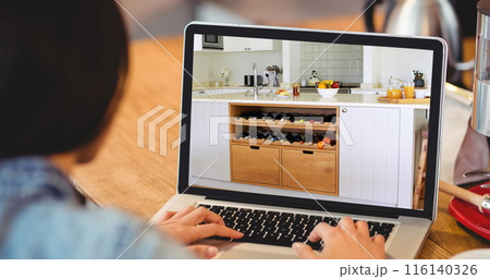 Image of person using laptop with house kitchen interiors displayed on screen 116140326