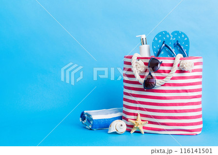 Stylish bag with beach accessories . Summer holiday concept. Top view of beach bag with sunscreen cream with space for text Stylish bag with beach accessories . Summer holiday concept. Top view of beach bag with sunscreen cream with space for text 116141501
