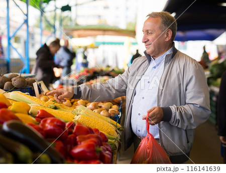 Middle aged man buying vegetables Middle aged man buying vegetables 116141639