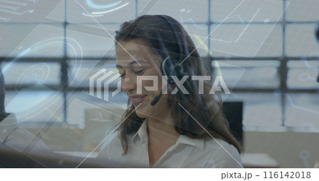 A young Caucasian woman wearing headset looking at computer screens 116142018