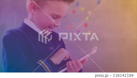 In school, boy in uniform using a tablet, colorful letters on wall behind In school, boy in uniform using a tablet, colorful letters on wall behind 116142189