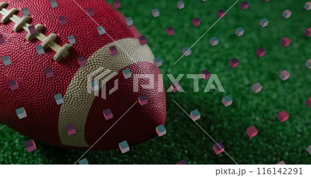 A close-up of football resting on green turf with confetti around A close-up of football resting on green turf with confetti around 116142291