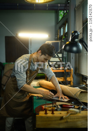 Tailor leather craftsman measuring leather for sewing at his workshop Tailor leather craftsman measuring leather for sewing at his workshop 116142870