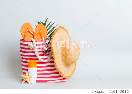 Stylish bag with beach accessories . Summer holiday concept. Top view of beach bag with sunscreen cream with space for text 116143016