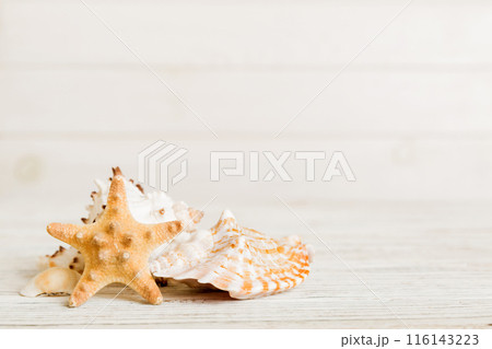 Summer time concept with sea shells or starfish on a table background with copy space for text 116143223