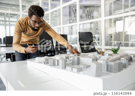 Young man in casual clothes working on miniature and looking involved 116143994