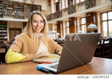 Smiling pretty woman working in the library 116144123