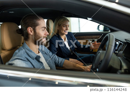 Young bearded man looking excited while sitting in a car before the test drive 116144248