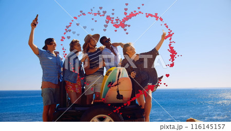 Image of hearts forming heart shape over multiracial friends taking selfie against sea and sky 116145157