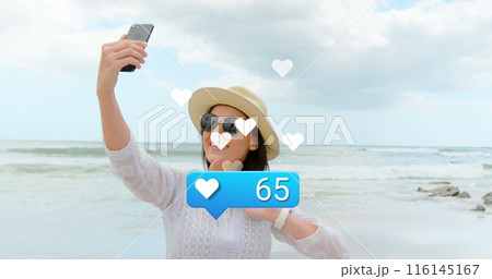 Image of hearts and social media reactions over happy caucasian woman taking photo on beach 116145167