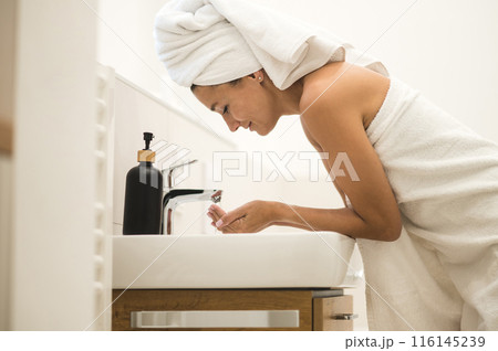 Woman washing her face in the morning Woman washing her face in the morning 116145239