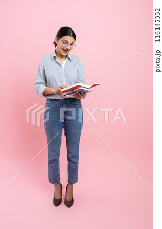 Full length of girl in casual shirt holding organizer reading information Full length of girl in casual shirt holding organizer reading information 116145332