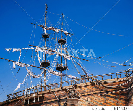 mast with sails on ancient wooden pirate ship on background of blue sky mast with sails on ancient wooden pirate ship on background of blue sky 116145389