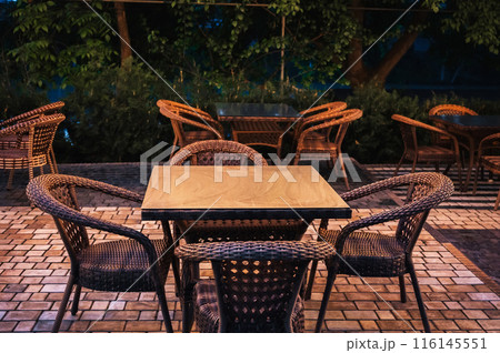 wooden tables and wicker chairs in an outdoor cafe in evening 116145551