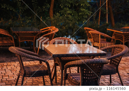 wooden table and vintage wicker chairs in an outdoor cafe in evening 116145560