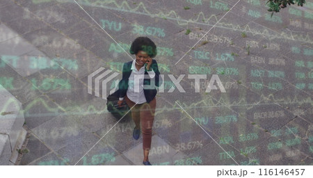 Image of trading board over african american woman talking on phone and walking with luggage 116146457
