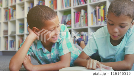 Two boys sitting on floor, reading together in colorful library 116146519