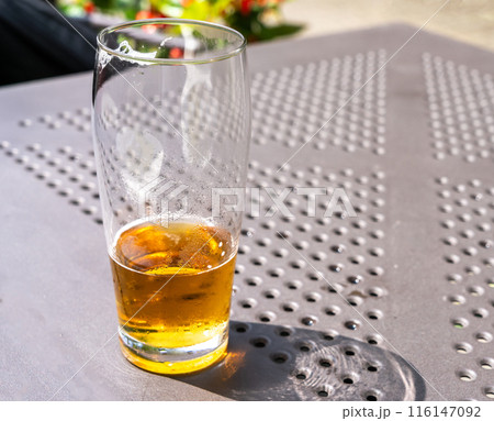 Beer glass in sunny day, cold pint glass with remaining beer on outdoor table, cool condensation 116147092
