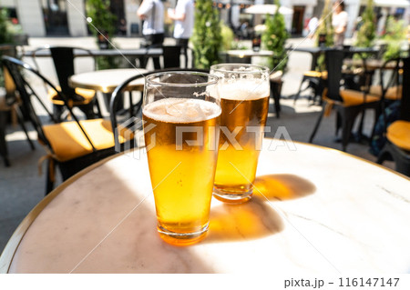 Beer glass in sunny day, cold pint glass with remaining beer on outdoor table, cool condensation Beer glass in sunny day, cold pint glass with remaining beer on outdoor table, cool condensation 116147147