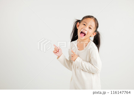 Happy Asian portrait cute young kid girl smiling indicate finger empty space, studio shot isolated on white background, Thai kindergarten child pointing index out with copy space 116147764