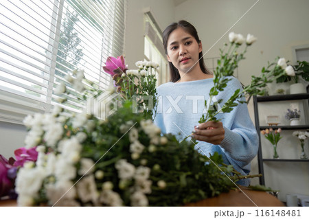 Woman Arranging Fresh Flowers at Home in a Bright and Modern Living Space with Natural Light Woman Arranging Fresh Flowers at Home in a Bright and Modern Living Space with Natural Light 116148481