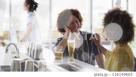Image of white spot lights over diverse friends having drink in bar Image of white spot lights over diverse friends having drink in bar 116149605