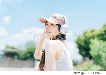 屋外で音楽を聴く若い女の子 116149666