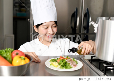 オリーブオイルをサラダにかける女性料理人 オリーブオイルをサラダにかける女性料理人 116150263