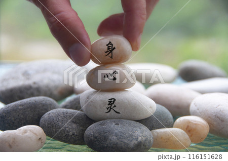 Hand placing Zen stone with body, mind and spirit in Chinese character. Zen concept Hand placing Zen stone with body, mind and spirit in Chinese character. Zen concept 116151628