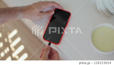 Closeup male hands connecting cable for transfer data. Unrecognizable man plugging cable into smartphone. Closeup male hands connecting cable for transfer data. Unrecognizable man plugging cable into smartphone. 116153014