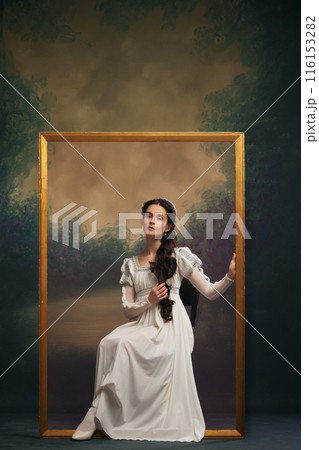 Portrait of elegant beautiful young girl in white dress sitting in golden frame against vintage background. Art-themed advertisements for galleries Portrait of elegant beautiful young girl in white dress sitting in golden frame against vintage background. Art-themed advertisements for galleries 116153282