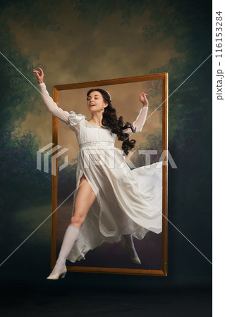 Advertisements for theatrical productions. Happy, smiling young girl in white medieval dress climbing out retro frame. Stepping into modern times 116153284